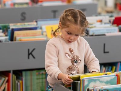 Lille pige kigger på billedbøger på biblioteket