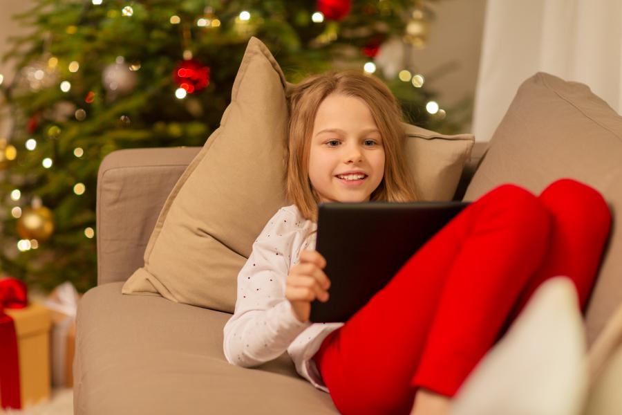 Pige læser foran juletræ